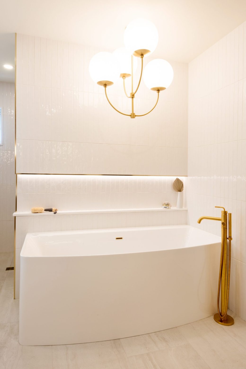 Crescent Living freestanding bathtub beneath a globe chandelier, with a gold-toned floor-mounted faucet