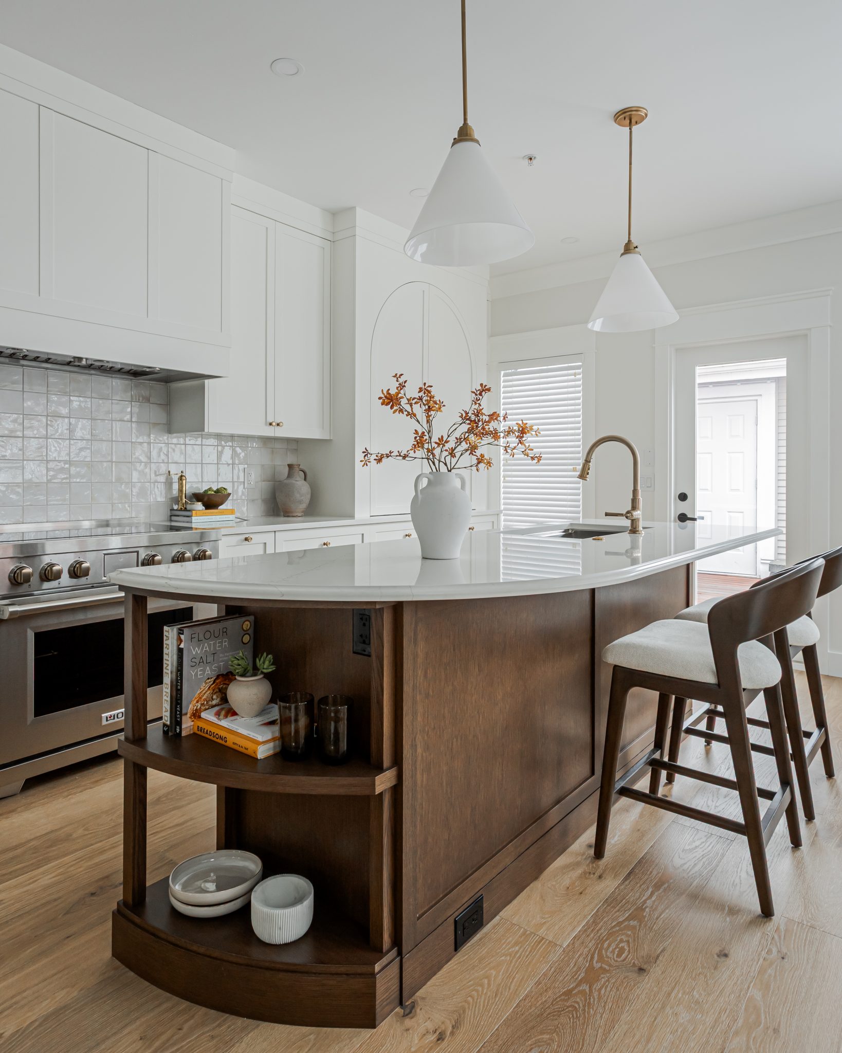 Hidden in Plain Sight kitchen island with a curved wood end, open shelves and white pendant lights