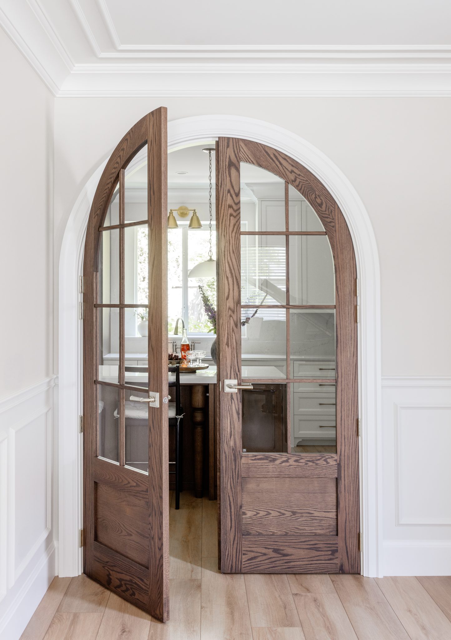 Partly open arched wood-and-glass double doors leading into the kitchen.