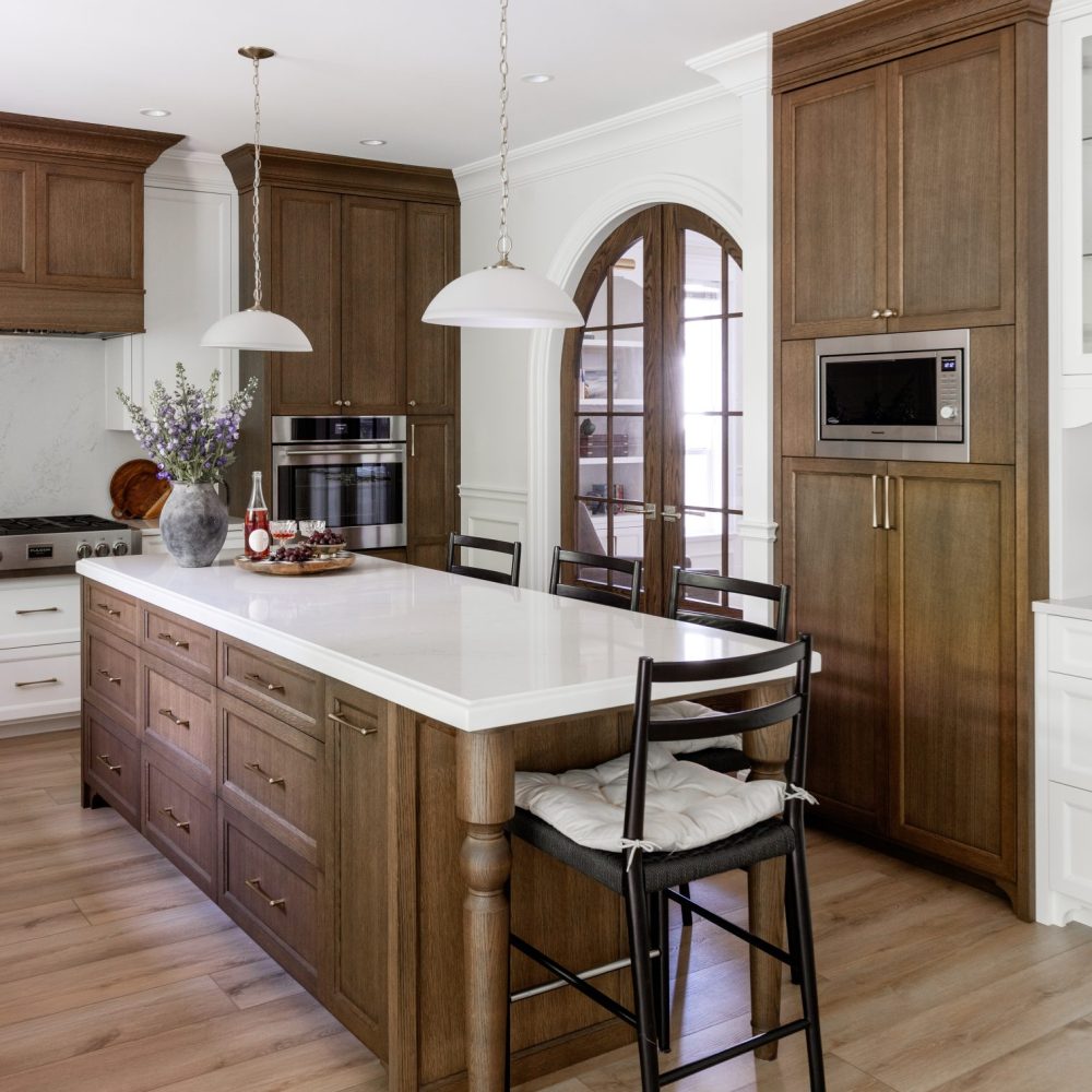Kitchen with a wood island, white countertops, dome pendant lights and arched glass doors.