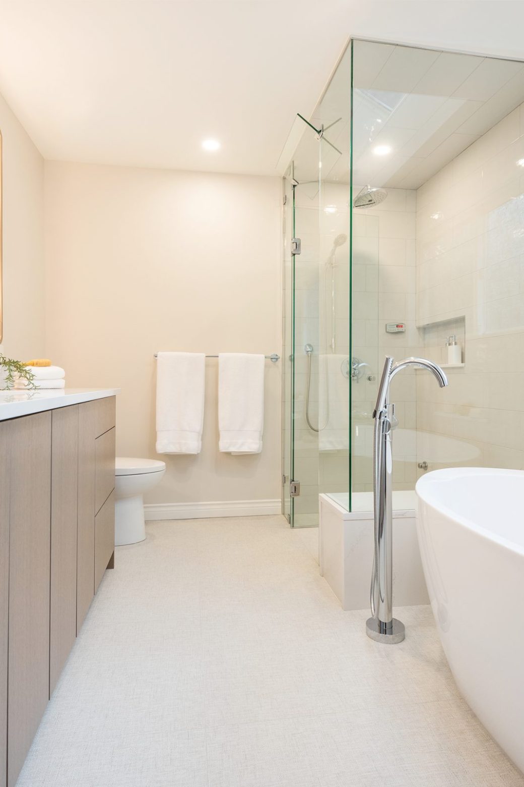 Bathroom with a long double vanity, freestanding tub and glass-enclosed shower.